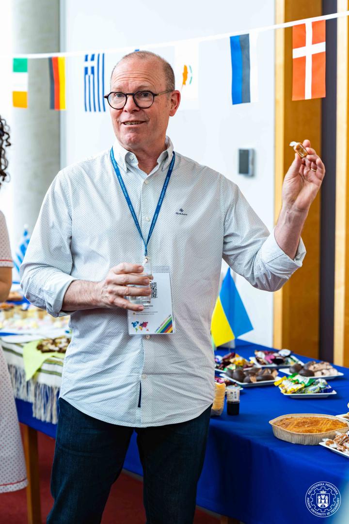 A male participant wearing glasses, holding a sweet snack against the background of a table