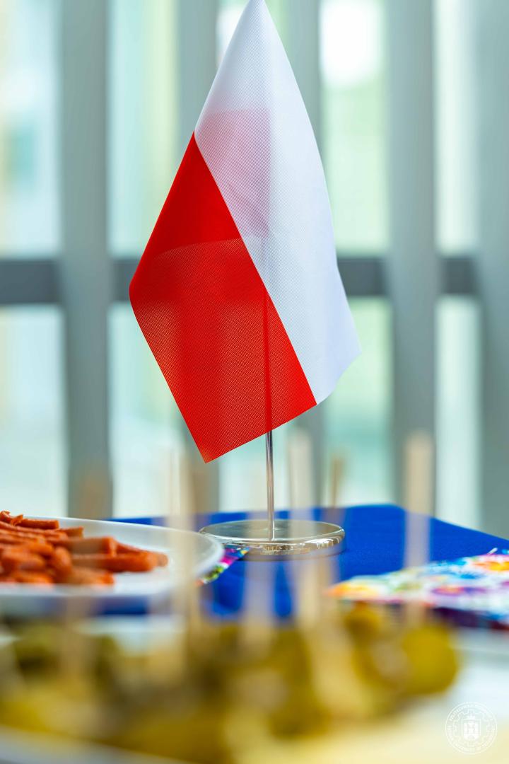 A small Polish flag standing on a table next to traditional snacks during a refreshment session.
