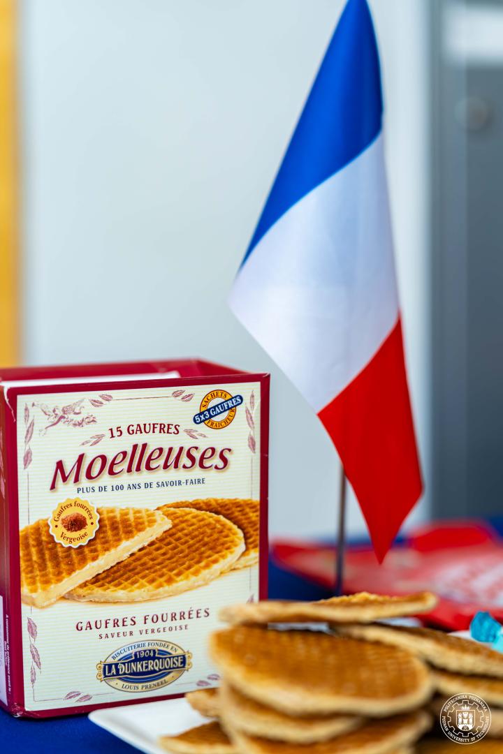 A small French flag standing on a table next to traditional snacks during a refreshment session.