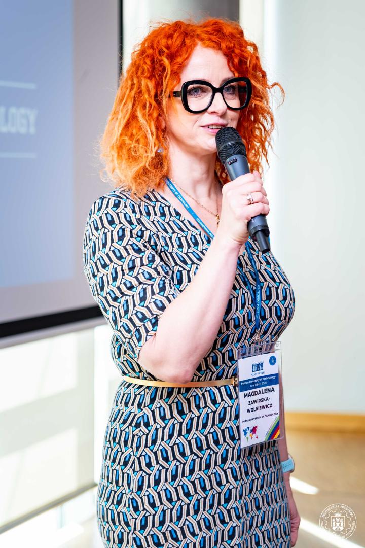 Magdalena Zawirska-Wolniewicz speaking into a microphone during a presentation.