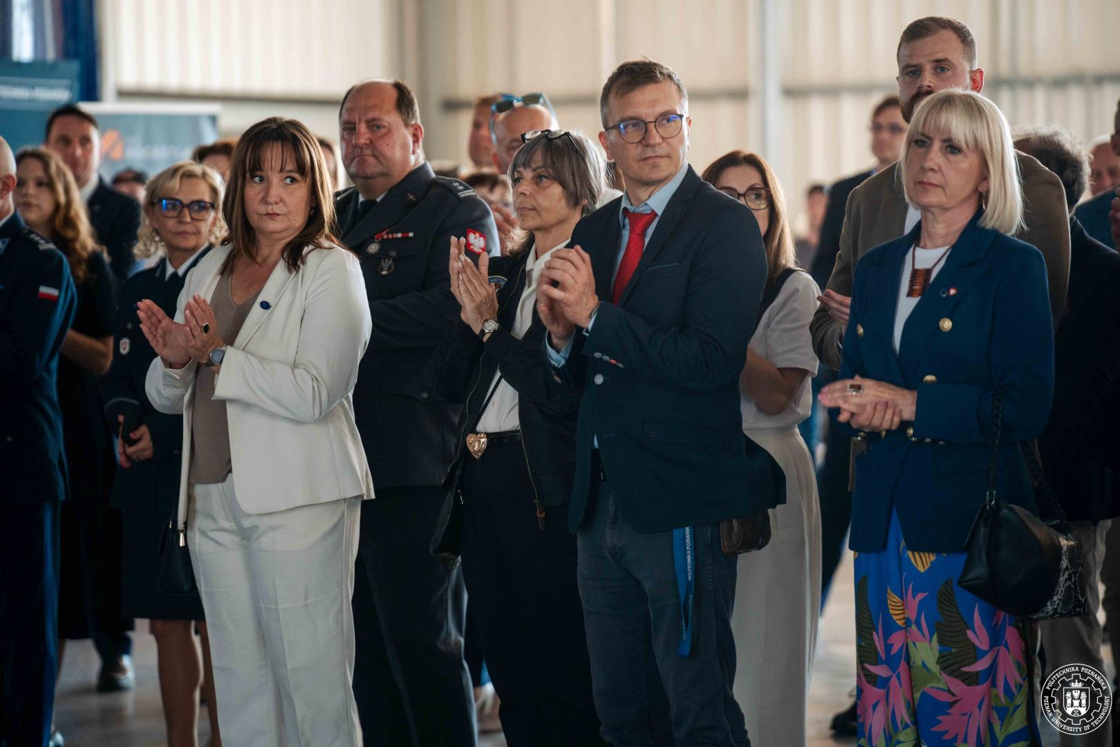 Goście i przedstawiciele uczelni klaszczący podczas powitania gości.