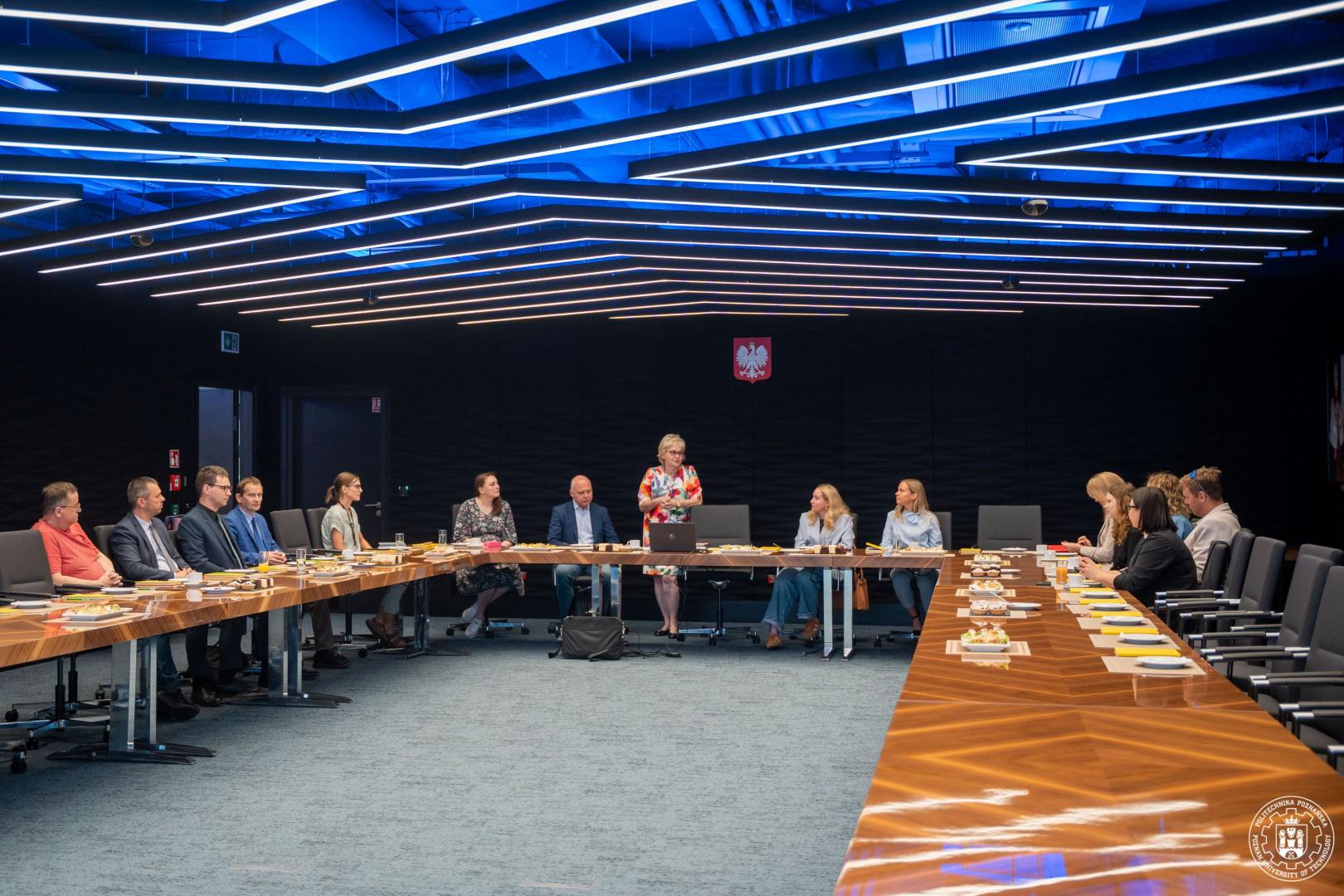 Spotkanie zespołu na Politechnice Poznańskiej poświęcone rozwojowi systemu mikropoświadczeń, uczestnicy przy stole konferencyjnym.