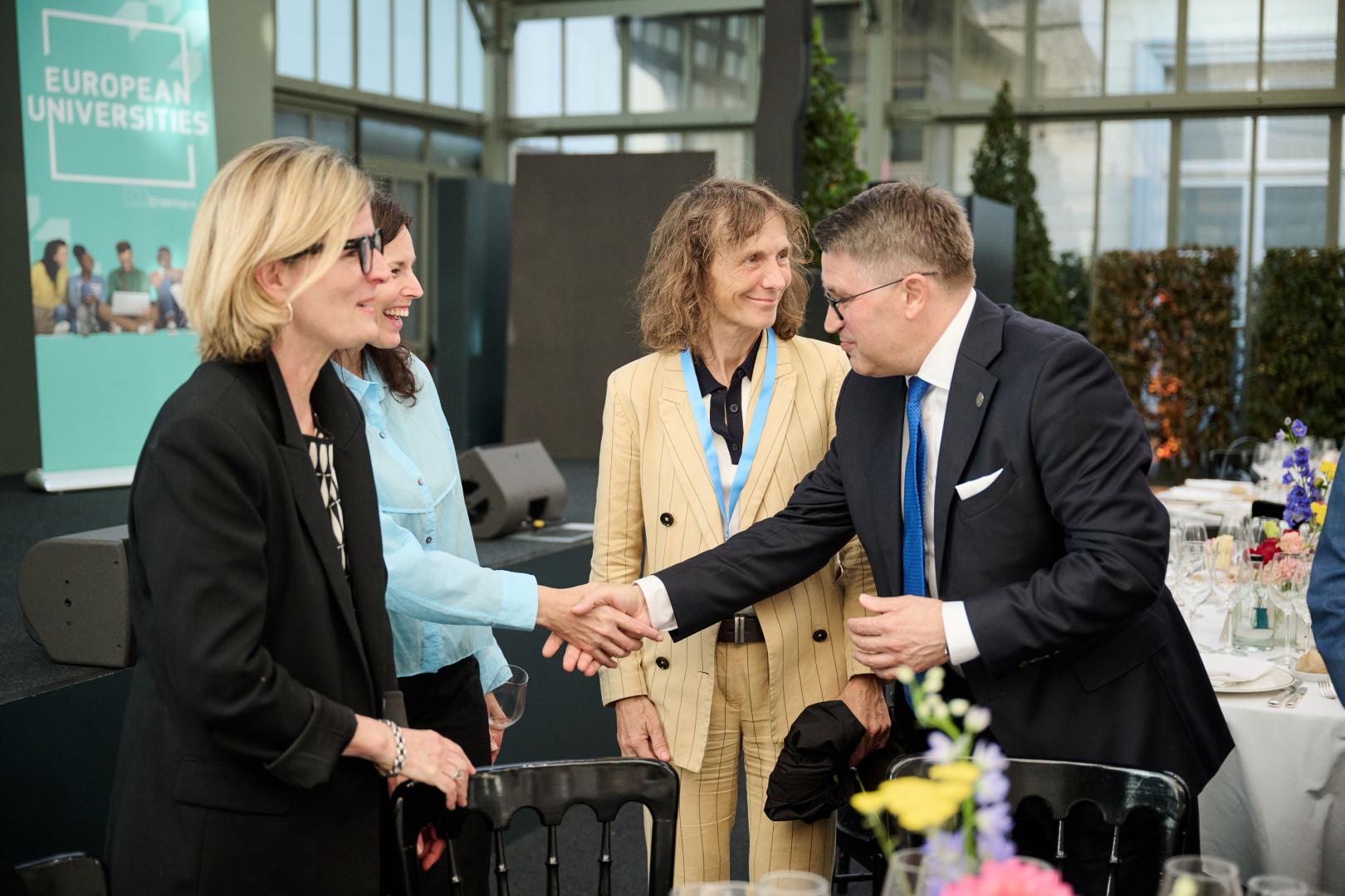Rektor Teofil Jesionowski wita się z uczestnikami spotkania Komisji Europejskiej, w tle widoczny baner „European Universities”.