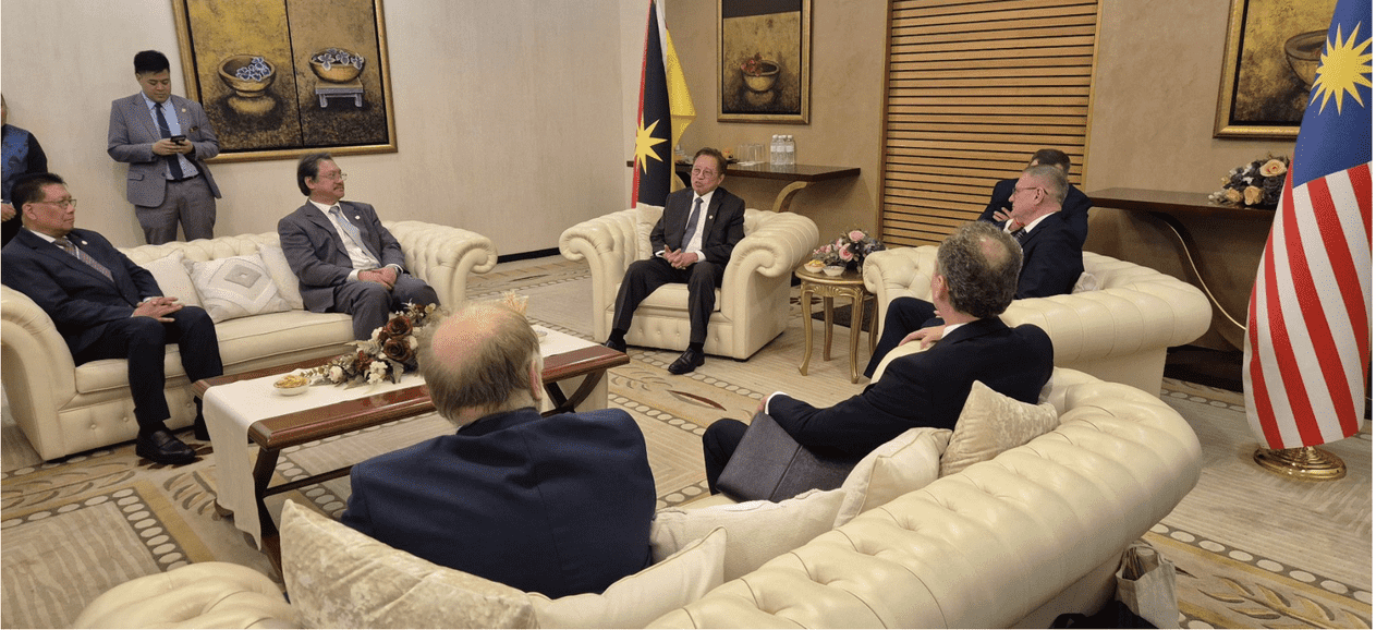 Oficjalne rozmowy dyplomatyczne i gospodarcze członków wielkopolskiej delegacji z władzami Stanu Sarawak w reprezentacyjnej sali spotkań, w tle widoczne flagi państwowe.