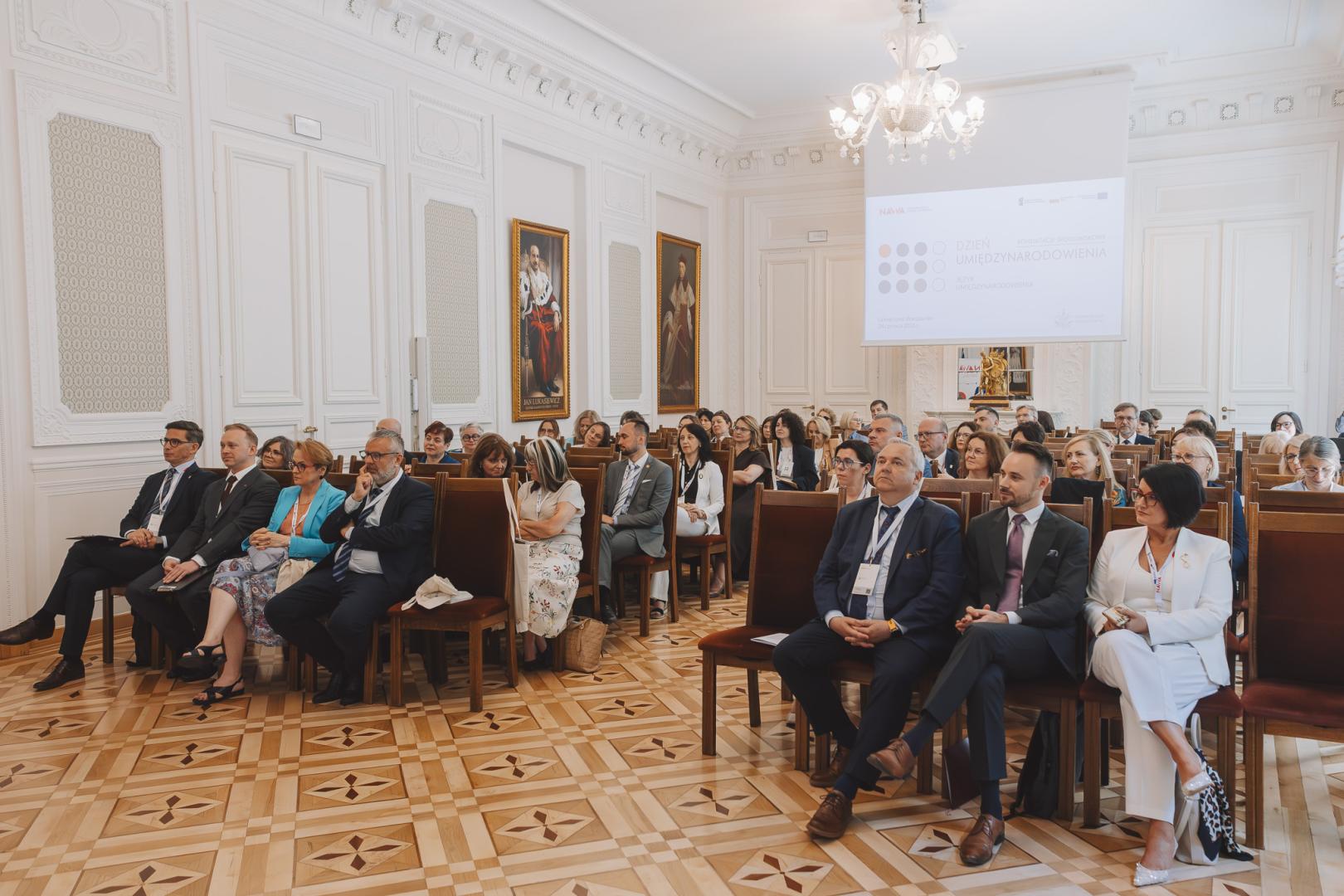 Uczestnicy konferencji NAWA „Dzień Umiędzynarodowienia” słuchają prelekcji w reprezentacyjnej sali Uniwersytetu Warszawskiego.