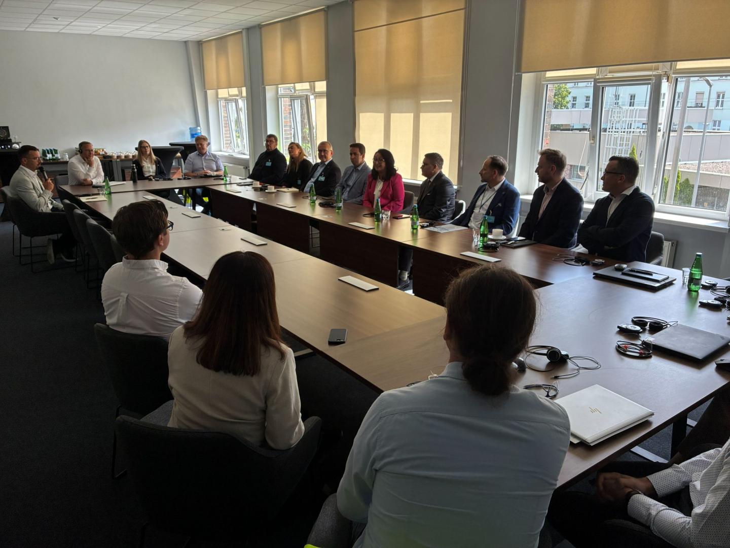 Uczestnicy spotkania siedzą przy stołach konferencyjnych podczas rozmów w Odlewni Volkswagen Poznań.