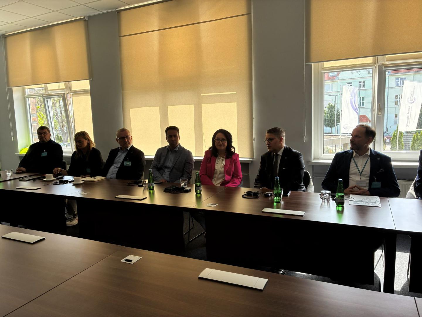 Uczestnicy spotkania siedzą przy długim stole konferencyjnym podczas rozmów w Odlewni Volkswagen Poznań.