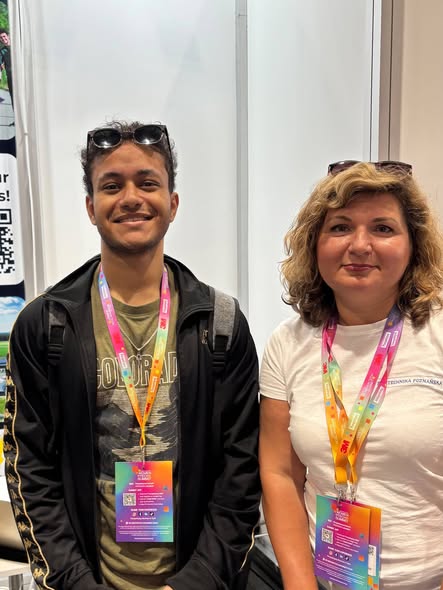Przedstawicielka Politechniki Poznańskiej rozmawia z uczestnikiem Perspektywy Women in Tech Summit przy stoisku uczelni.