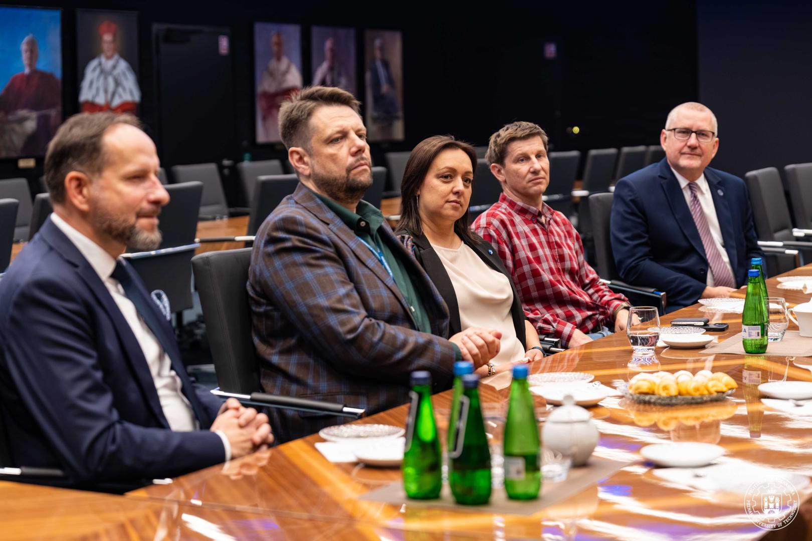 Uczestnicy spotkania siedzą przy stole konferencyjnym podczas rozmów Politechniki Poznańskiej z RECARO.