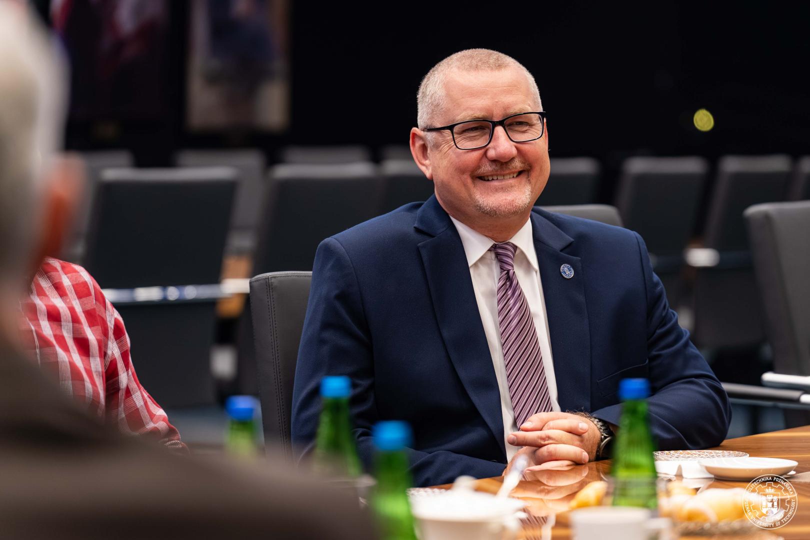 Przedstawiciel Politechniki Poznańskiej rozmawia przy stole konferencyjnym podczas spotkania z firmą RECARO.