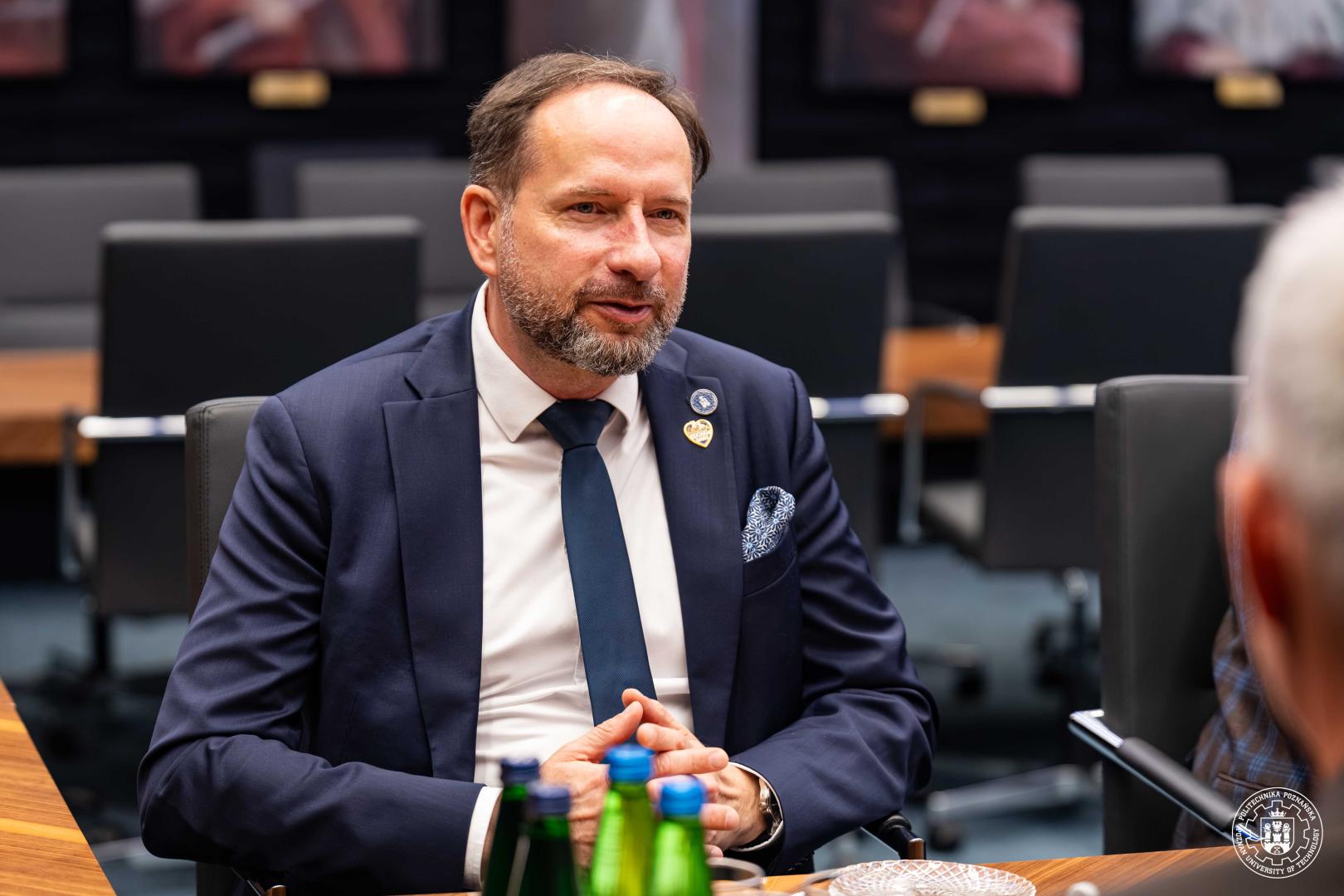 Prorektor Politechniki Poznańskiej dr hab. Arkadiusz Ptak, prof. PP  rozmawia przy stole konferm podczas spotkania z przedstawicielami firmy RECARO.