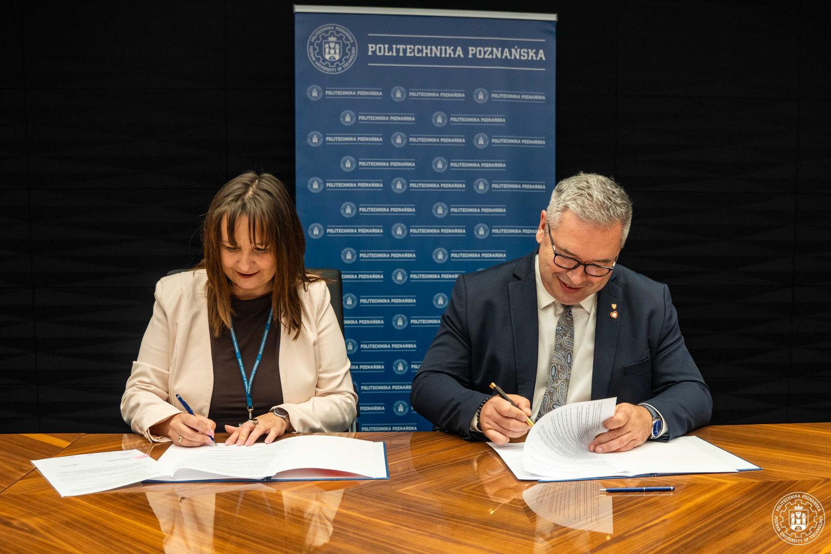Jacek Bogusławski i dr hab. inż. Agnieszka Misztal podpisują porozumienie przy stole, w tle logo Politechniki Poznańskiej.