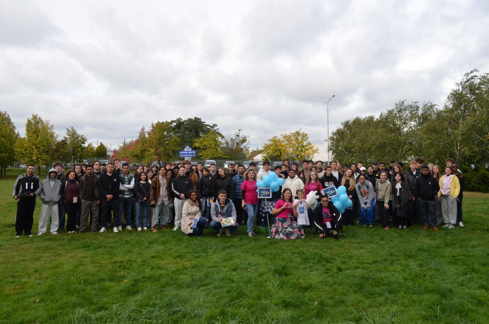 A large group of international students and organizers poses for a commemorative group photo on the campus lawn of Poznan University of Technology.  