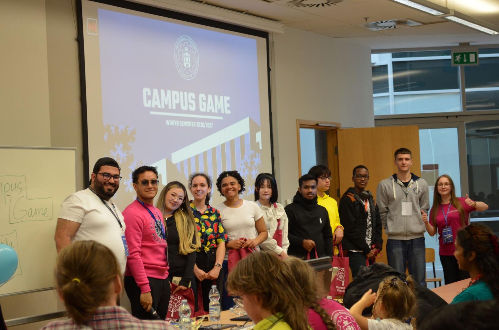 Event participants pose in a lecture hall in front of a screen reading "CAMPUS GAME Winter Semester 2026/2027".