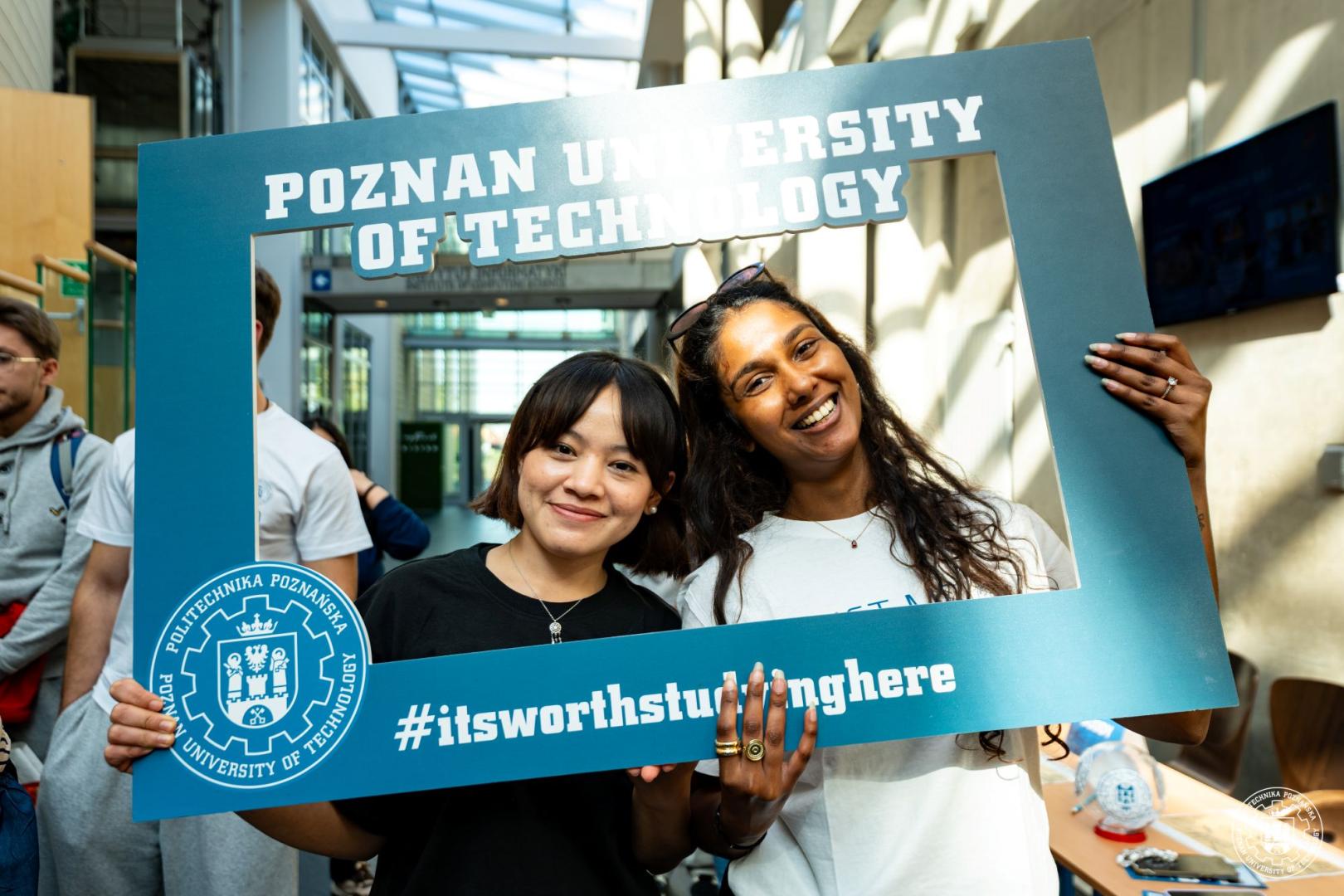 Dwie uśmiechnięte studentki zagraniczne pozują z ramką z napisem Poznan University of Technology