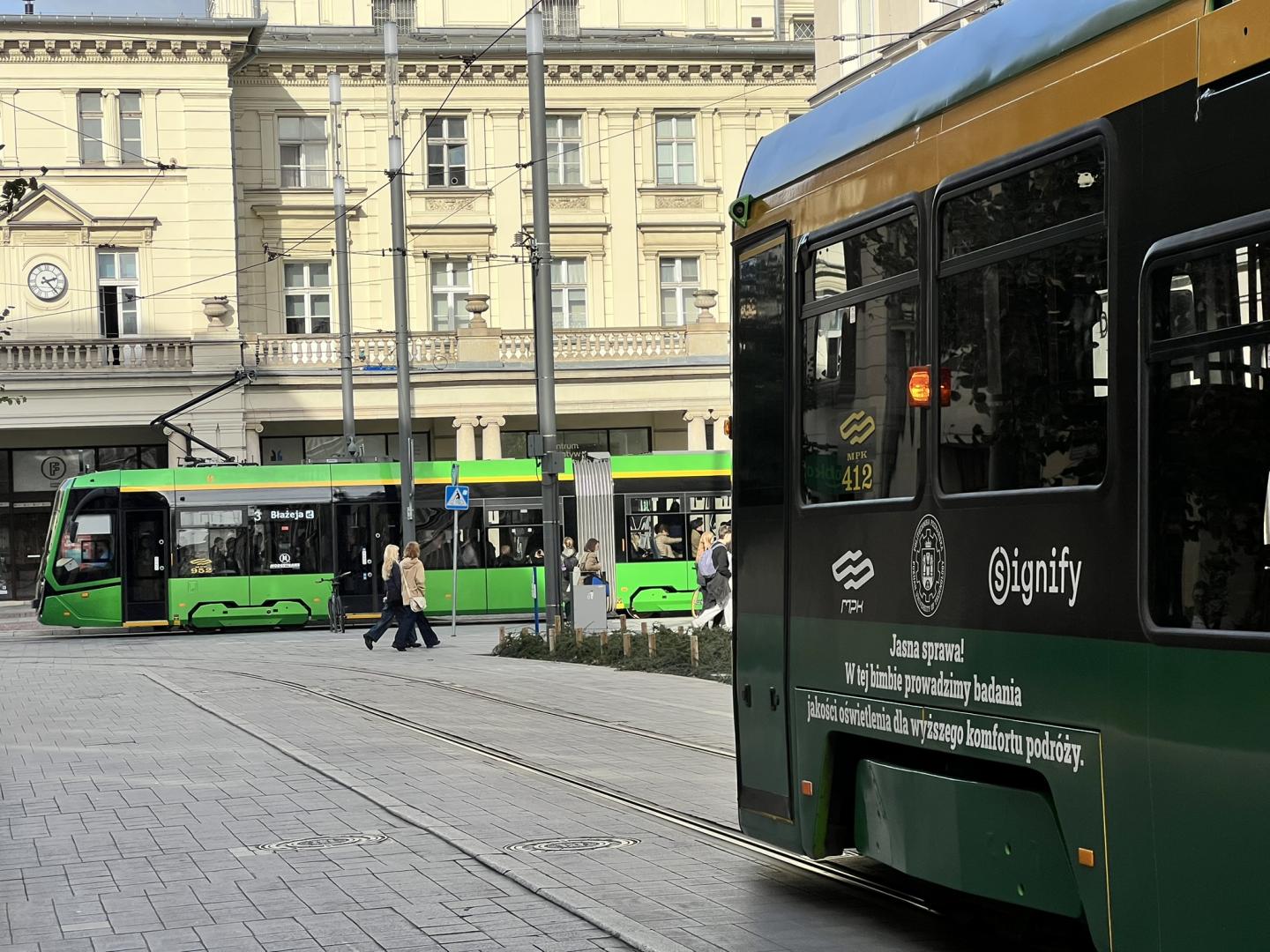 Tramwaj MPK Poznań z napisem „Jasna sprawa! W tej bimbie prowadzimy badania jakości oświetlenia dla wyższego komfortu podróży” oraz logo Signify, Politechniki Poznańskiej i MPK Poznań.