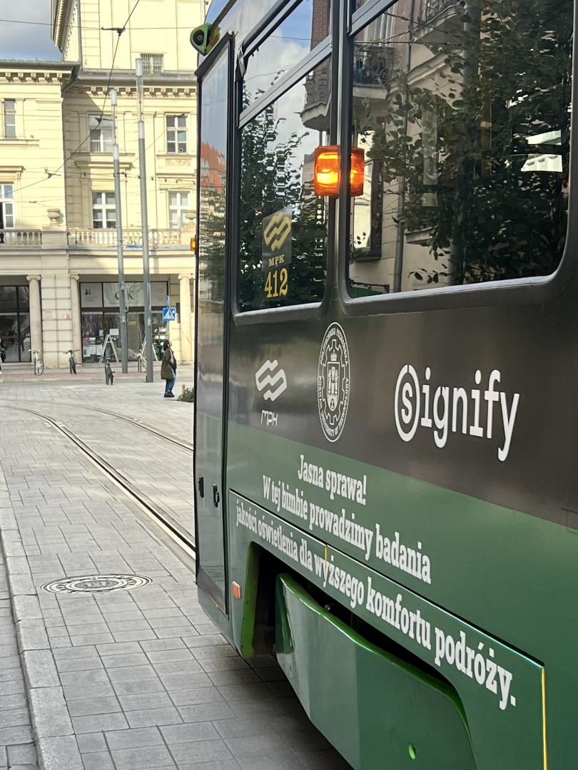 Zbliżenie na bok tramwaju MPK Poznań z logo MPK, Politechniki Poznańskiej i Signify oraz napisem „Jasna sprawa! W tej bimbie prowadzimy badania jakości oświetlenia dla wyższego komfortu podróży”.