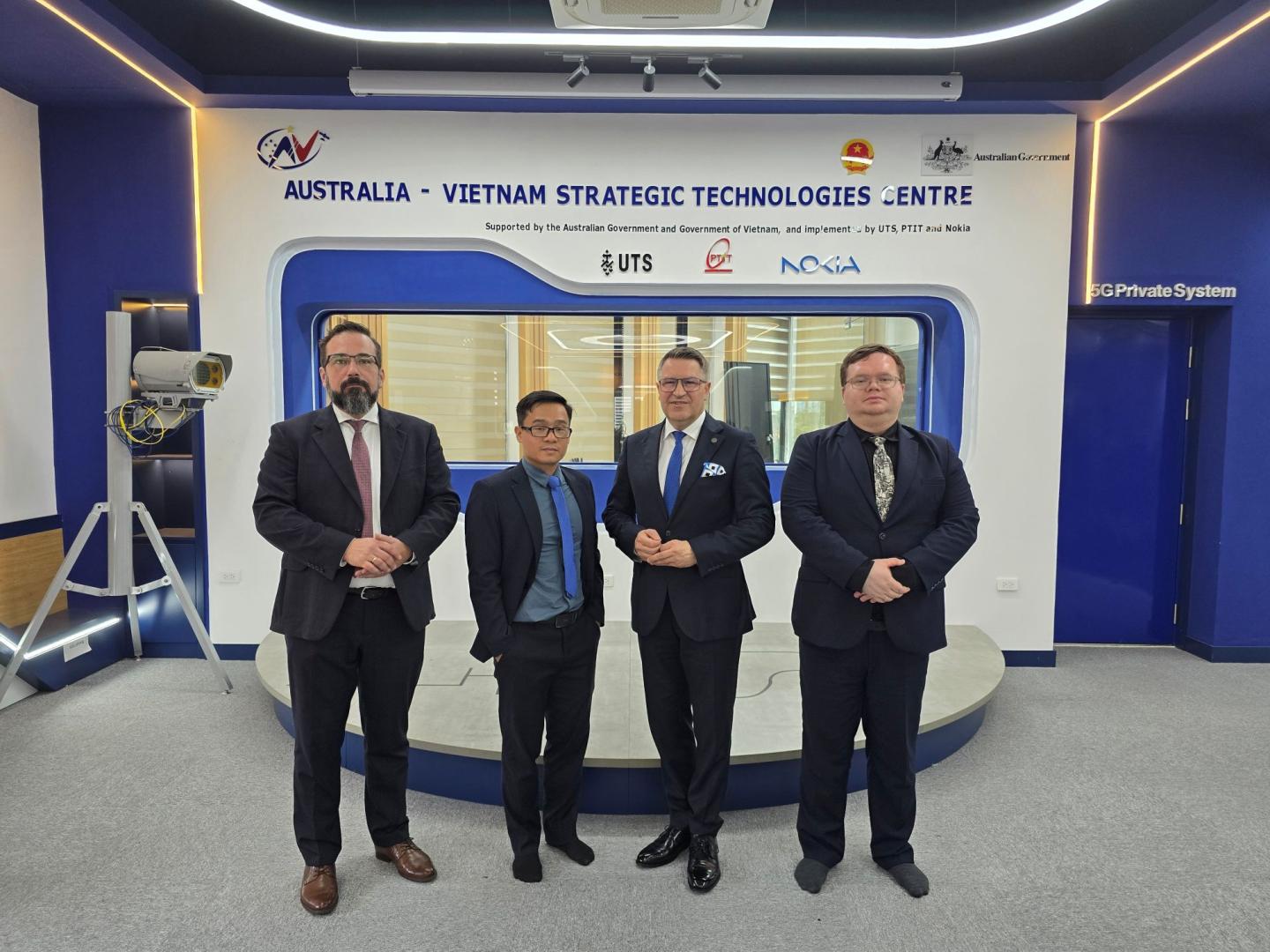 Przedstawiciele Politechniki Poznańskiej w Australia-Vietnam Strategic Technologies Centre na tle napisów i logo uczelni oraz partnerów technologia 5G.