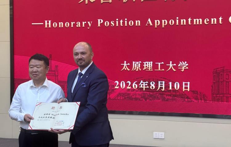 Prof. Wojciech Sumelka i prof. Xingquan Shen trzymają otwarty dokument z tytułem honorowym, na tle czerwonej ściany z napisem "Honorary Position Appointment Ceremony" i datą 2026年8月10日.
