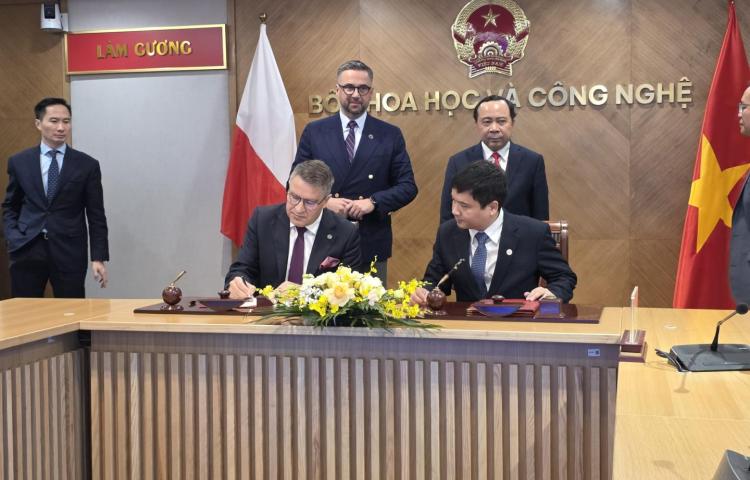 Rektorzy Politechniki Poznańskiej i uczelni PTIT podpisują dokumenty przy stole, w obecności przedstawicieli władz i flag Polski oraz Wietnamu.